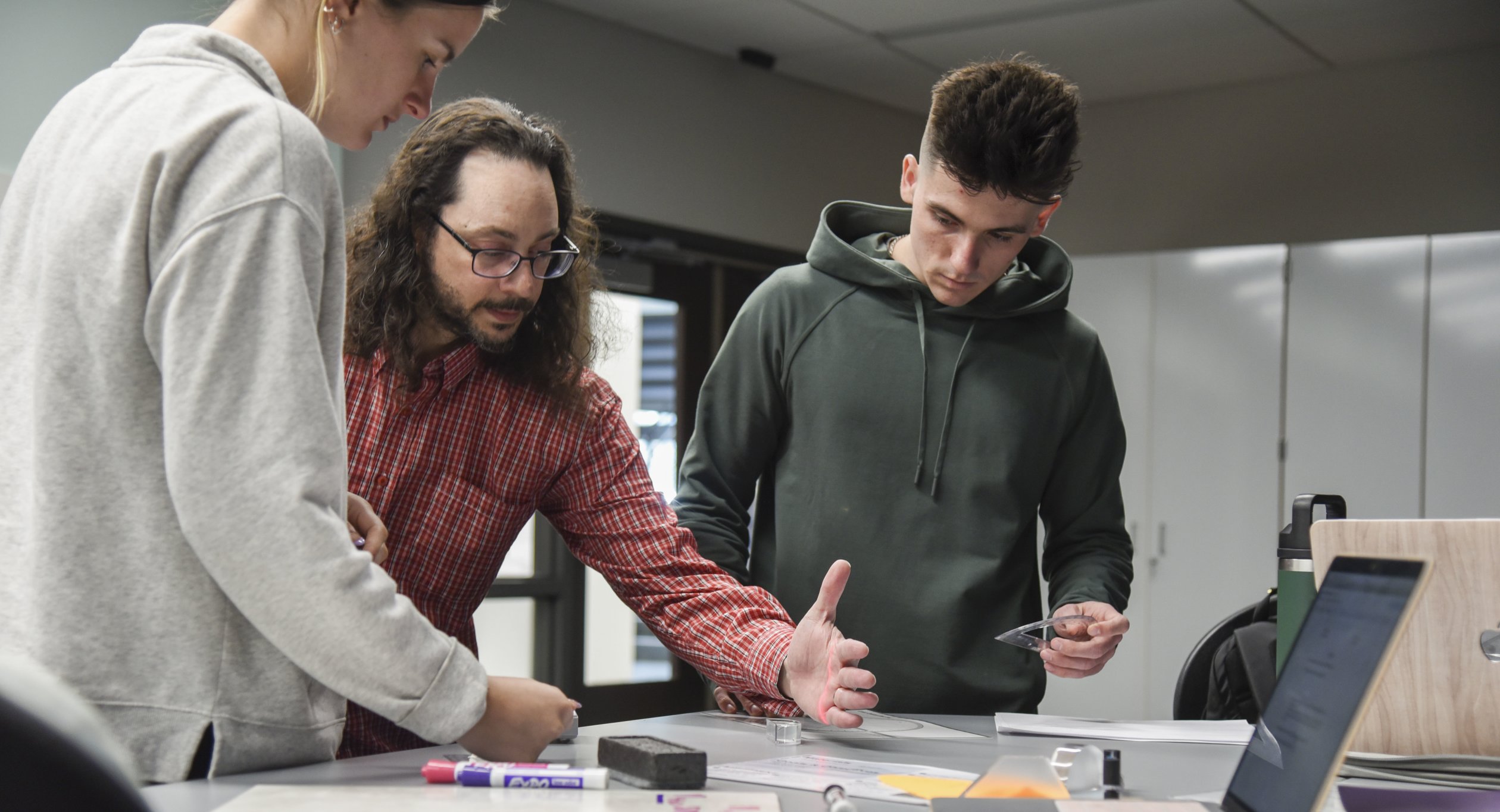 Jon Gaffney teaching Physics with students at a table.