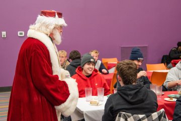 Santa Claus visits with students at the 2025 Holiday Dinner.