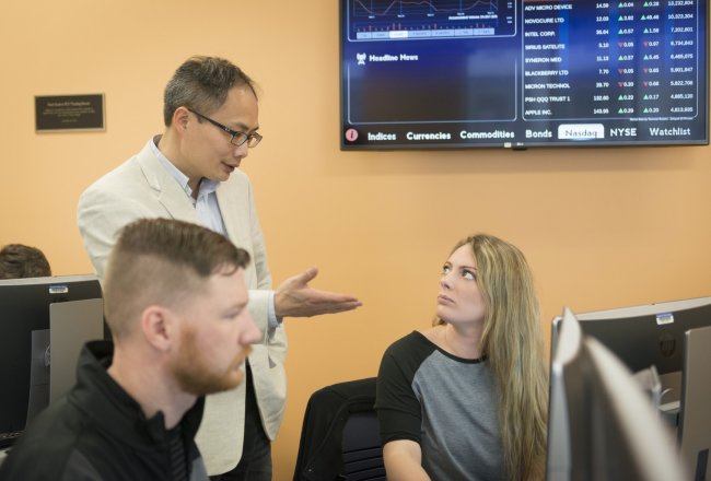 Business Prof Zhaodan Huang talks with student Stock info behind