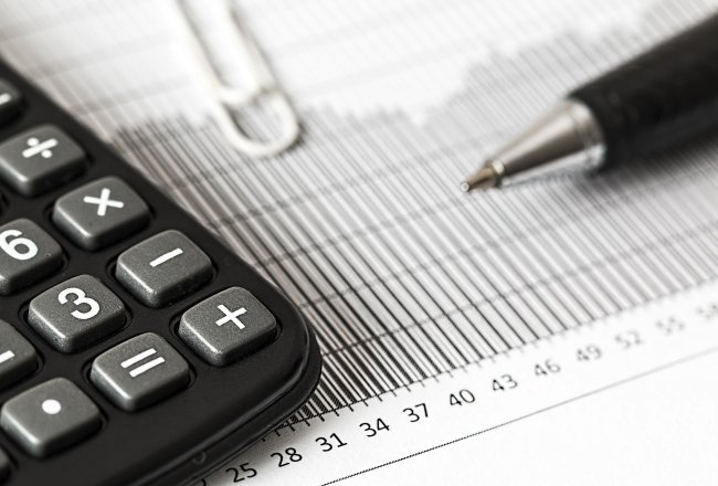 A calculator and pen sit on top of a piece of paper.