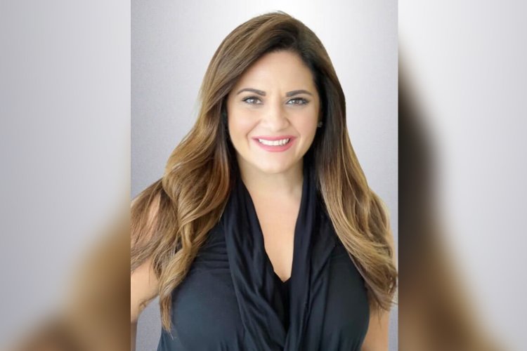 Angela Grande '05 in black dress against a gray background. 