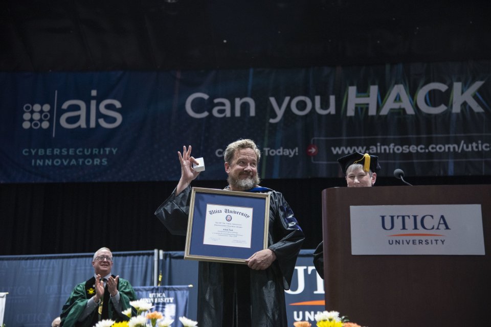 Dr. Adam Pack holds up the framed Crisafulli Award at the 2024 Commencement Ceremony.