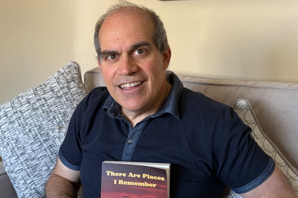 Mike Dileo '89 in blue polo shirt, holds a copy of his book - "There are Places I Remember."